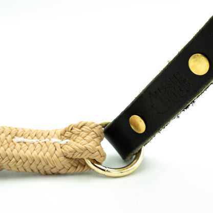 Dog leash with braided design and black leather handle on a white background Sand