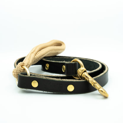 Black leather dog leash with gold accents and rope handle on a white background Sand